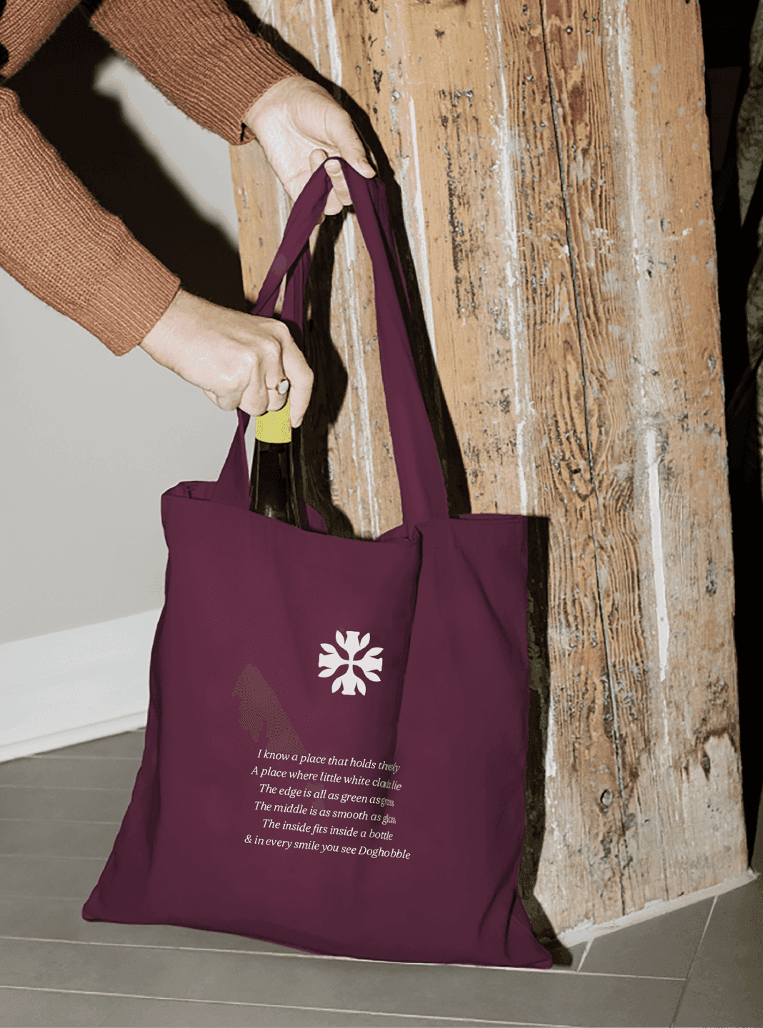 Doghobble Wine Farm Tote Bag. A plum tote bag with the Doghobble Wine Farm emblem and brand message, shown carrying a bottle.