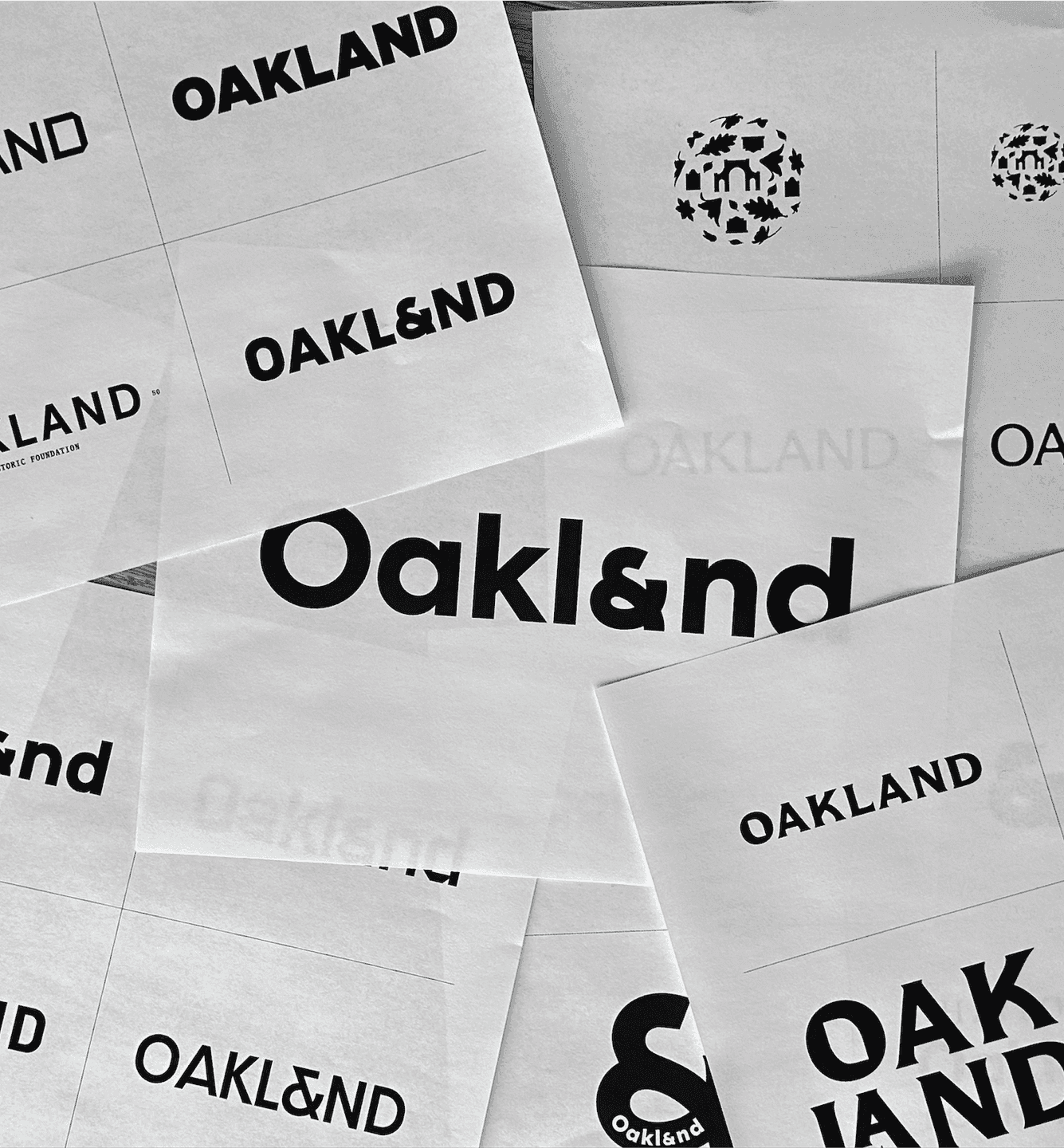 A collection of black-and-white Oakland logo explorations and typography studies spread across printed sheets.
