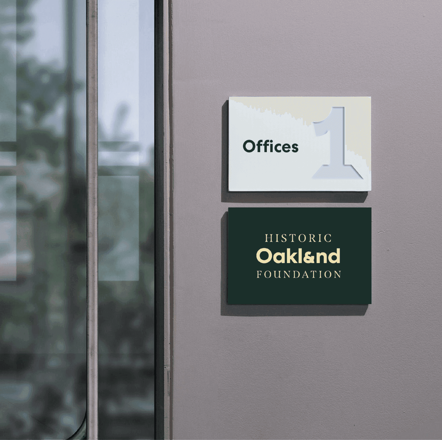 Interior signage for the Historic Oakland Foundation features the Oakland wordmark on a dark plaque beside a minimalist office number sign.